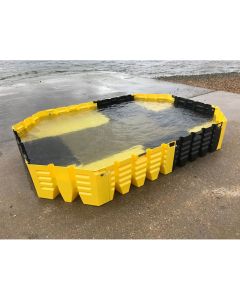 Modular yellow and black flood barrier system fully assembled and filled with water on a concrete coastal ramp
